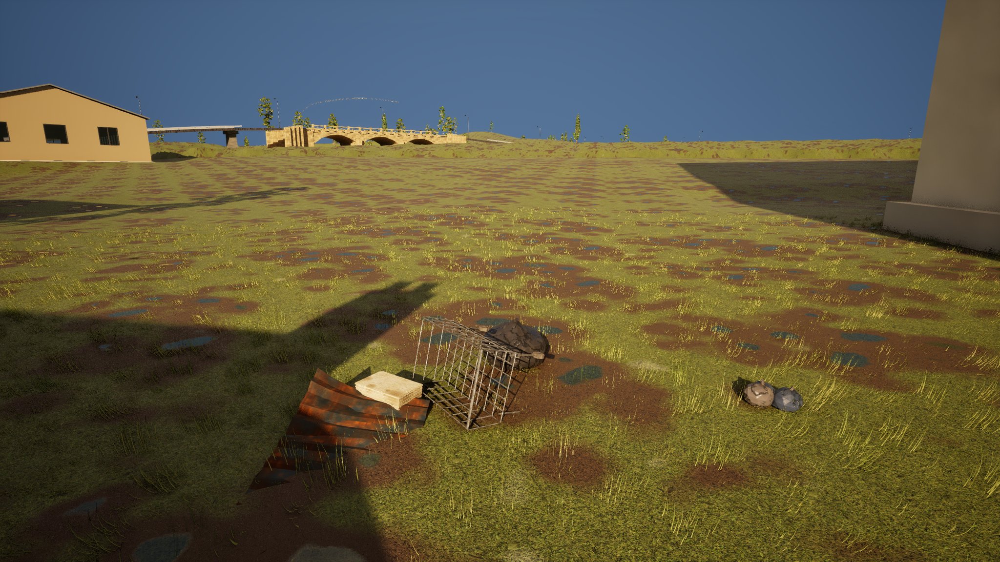 Fly-tipped rubbish on rough grass: a sheet of corrugated iron, a wire cage trolley and rubble sacks, with a stone arch bridge on the skyline behind.