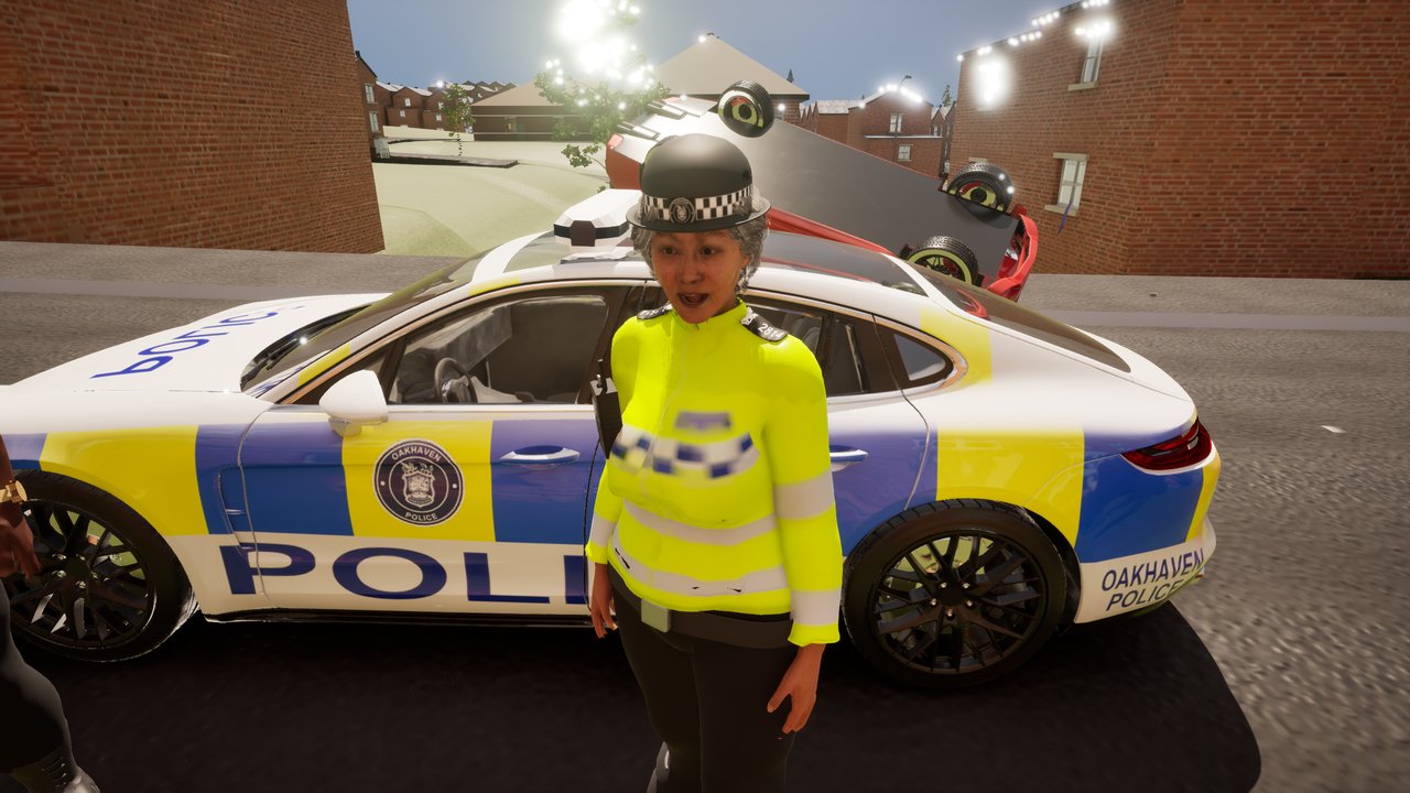 A police officer mid-lecture on the pavement beside a liveried Oakhaven Police car, terraced houses behind.