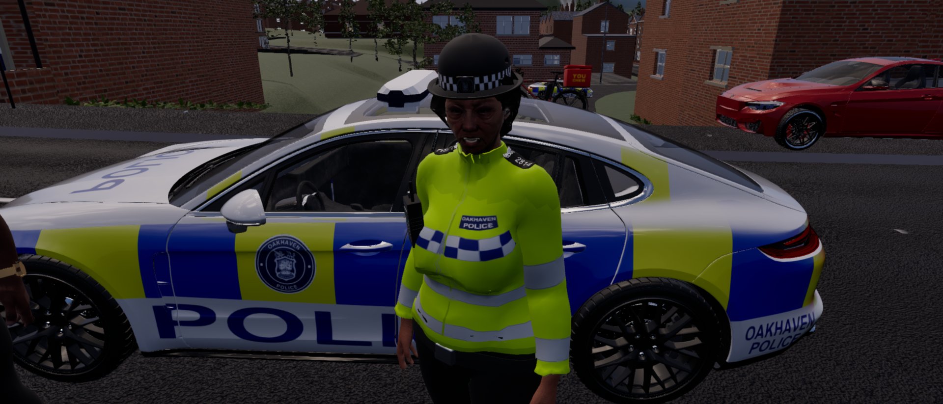A police officer in a hi-vis jacket marked OAKHAVEN POLICE and a checked bowler hat stands in front of a patrol car in blue and yellow checks, on a terraced street with a red car parked behind.
